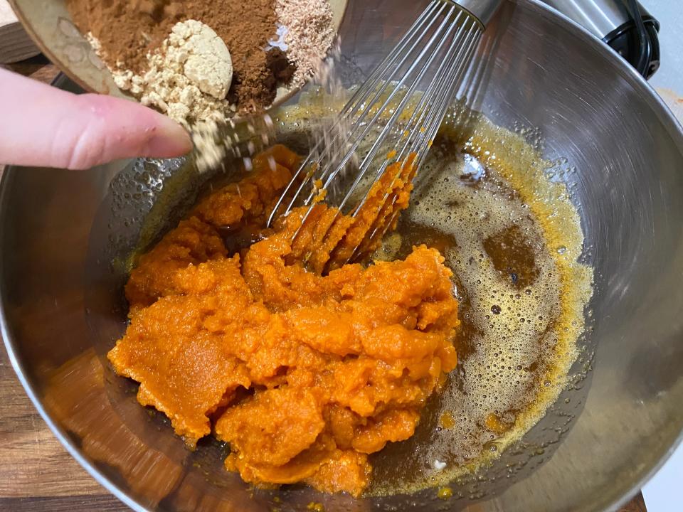 The writer pouring the ingredients for Bobby Flay's pumpkin pie filling in a metal bowl with a whisk