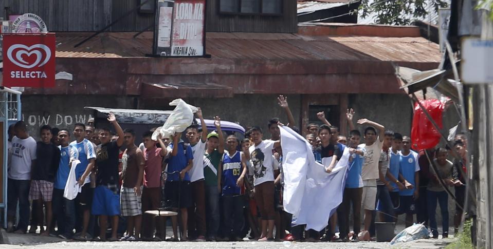 Residents believed to be hostages of Moro National Liberation Front rebels wave white cloth and shout to the government soldiers "stop firing" while standing in the rebels' positions in downtown Zamboanga City