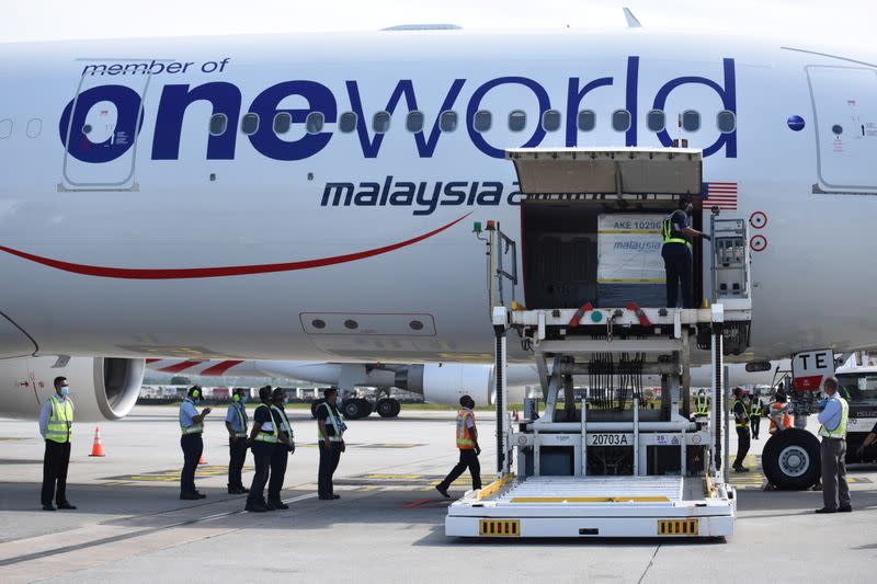 Containers carrying the first batch of Pfizer-BioNTech COVID-19 vaccines are unloaded from a plane at the MASkargo Complex in Sepang