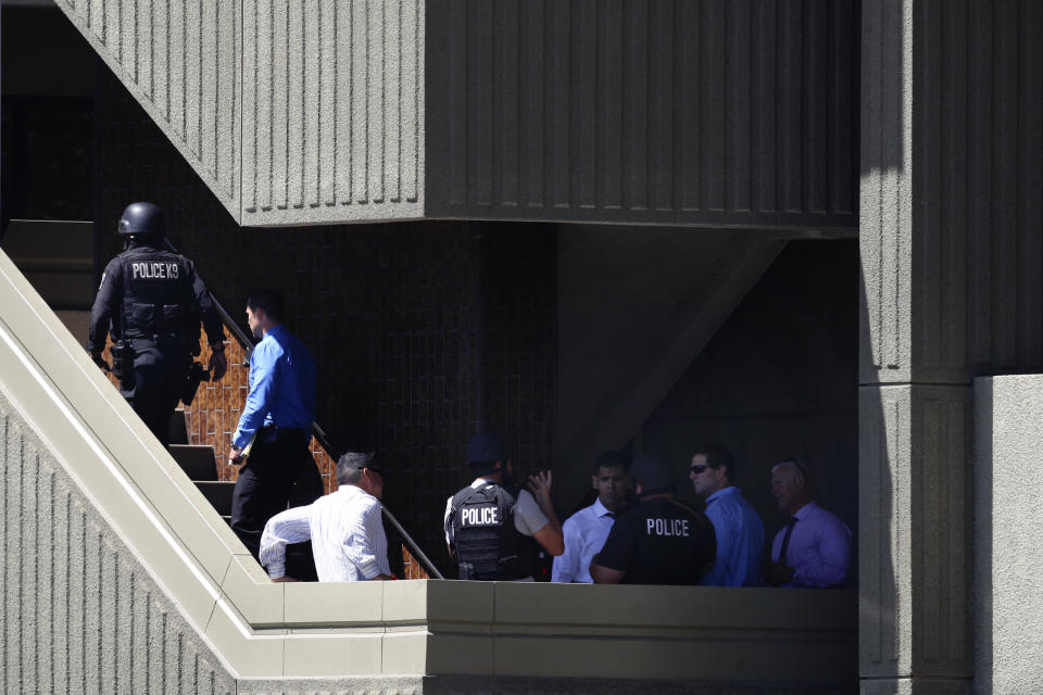 Investigators gather around the steps of Kaiser Permanente Downey Medical Center, Tuesday, Sept. 11, 2018, in Downey, Calif, following reports of someone with a weapon at the facility. Los Angeles County sheriff's officials say a suspect is in custody and deputies and police officers are methodically searching the complex. (AP Photo/Jae C. Hong)