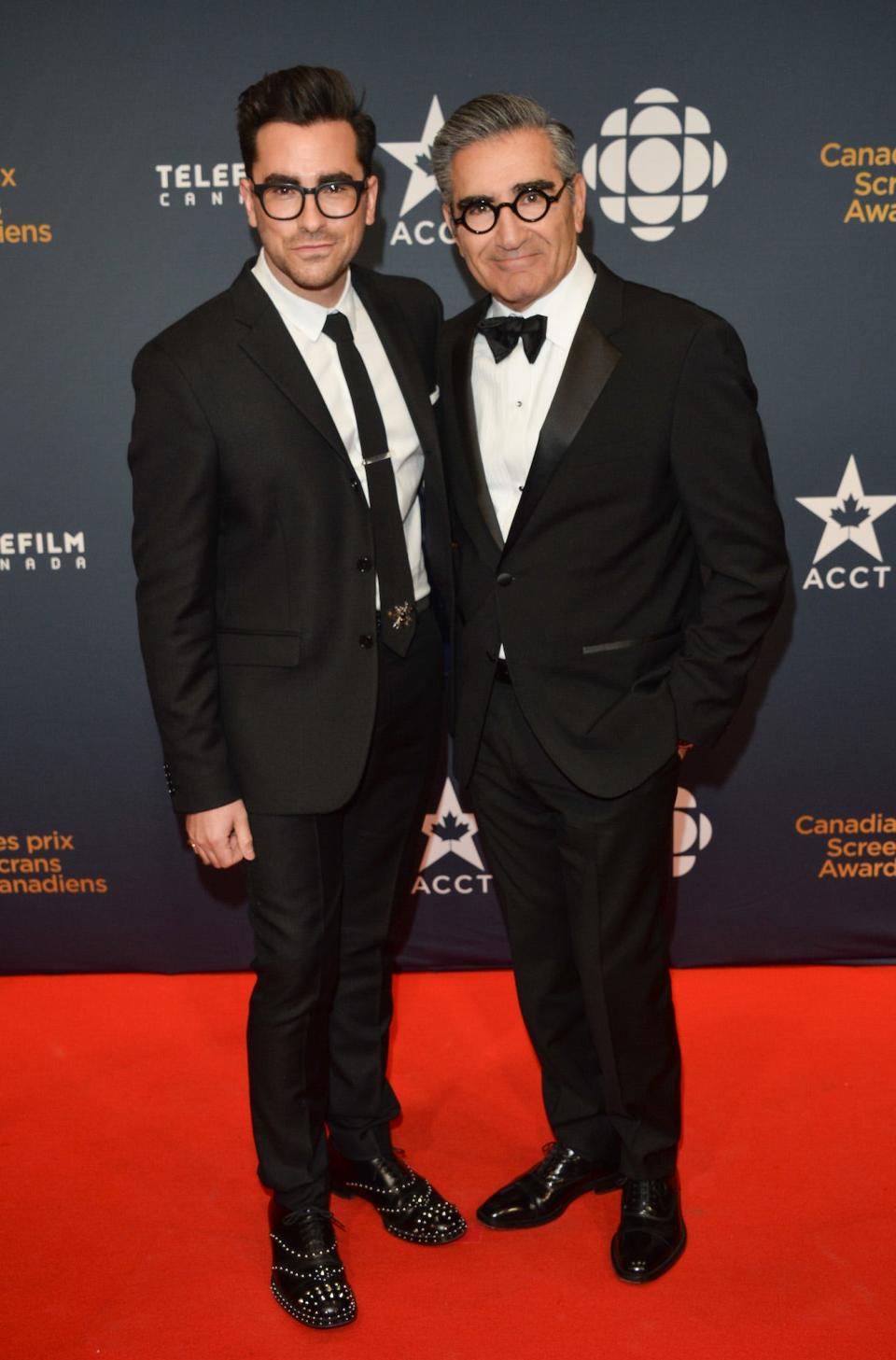 Dan Levy and Eugene Levy pose together in suits and glasses at the 2015 Canadian Screen Awards.