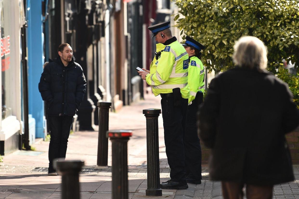 Police community support officers talk to a man on a street in Brighton, southern England on March 24, 2020 after the British government ordered a lockdown to help stop the spread of coronavirus: AFP