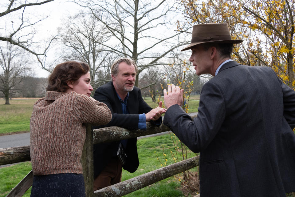 L to R: Emily Blunt (as Kitty Oppenheimer) with writer, director, and producer Christopher Nolan and Cillian Murphy (as J. Robert Oppenheimer) on the set of OPPENHEIMER.