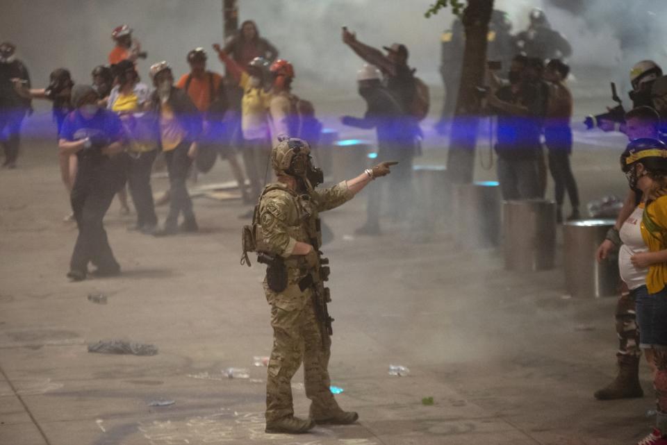 A federal officer points to a protester while clearing the street in front of the federal courthouse.