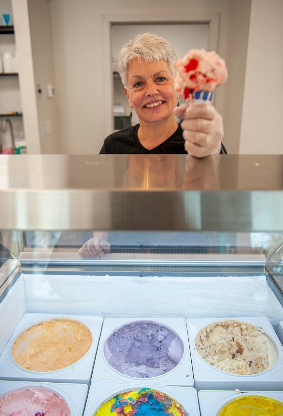 T.C. Scoops owner Tina Chemini shows off an ice cream cone inside her new store on Central Street in Holliston, April 19, 2023.