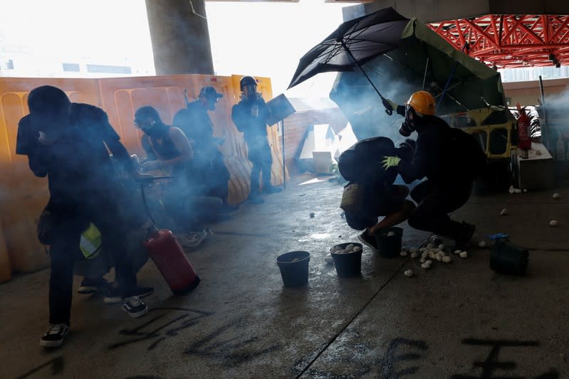 Smoke is seen as protesters shield with an umbrella at Hong Kong Polytechnic University in Hong Kong