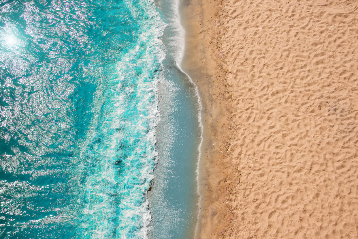 Coastline Beach Ocean waves with foam on the sand. Top view from drone