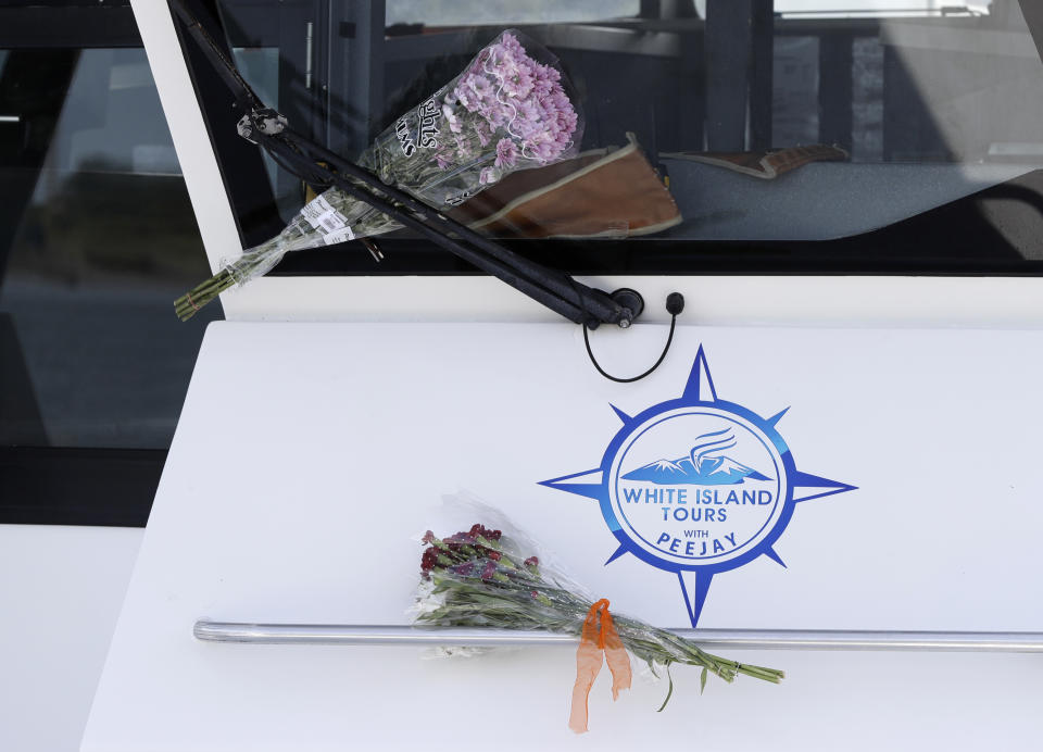 Bouquets of flowers sit on one of the two tour boats that went to White Island on Dec. 9 in Whakatane, New Zealand, Wednesday, Dec. 11, 2019. Survivors of a powerful volcanic eruption in New Zealand on Monday ran into the sea to escape the scalding steam and ash and emerged covered in burns, say those who first helped them. (AP Photo/Mark Baker)