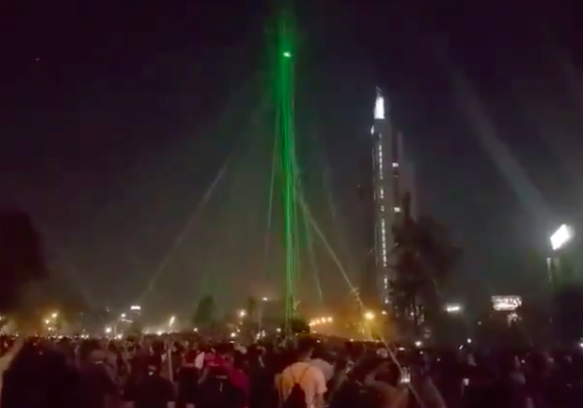 Manifestantes derriban a un dron con sus punteros láser en la Plaza Italia de Santiago de Chile. Captura Twitter