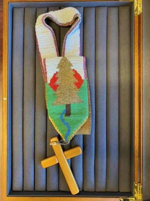 The pectoral cross was made by two of the lay readers at Christ Church, Earl J. Brant and Arnold J. Brant. It was made of white pine and beadwork on leather. The cross included symbols important to the Kanien'kehá:ka such as the Great White Tree of Peace. 