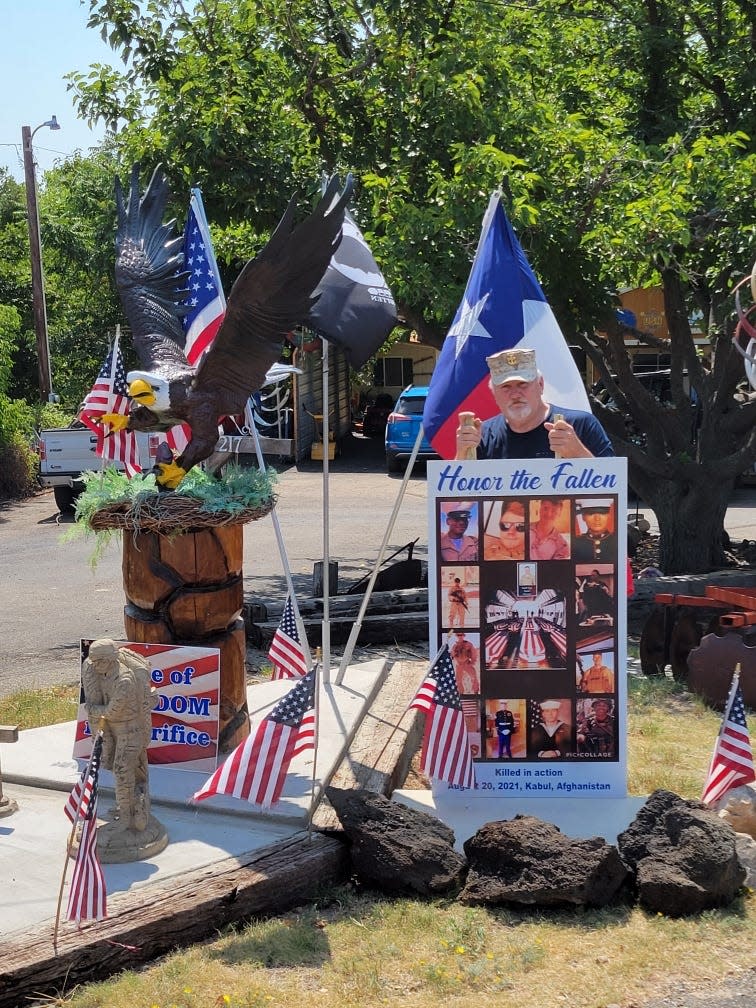 Donald "Buck" McLamb Marine and Navy Seebee veteran stands in his yard monument saluting fallen veterans at his home.