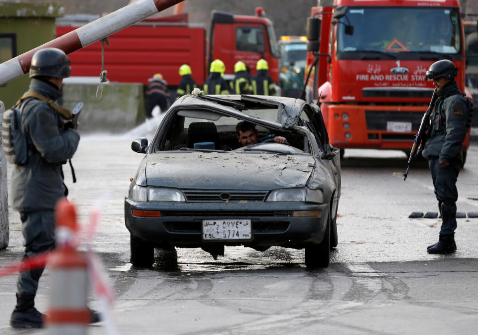 <p>Afghan police officers keep watch while a man drives his damaged car at the site of a car bomb attack in Kabul, Afghanistan, Jan. 27, 2018. (Photo: Omar Sobhani/Reuters) </p>