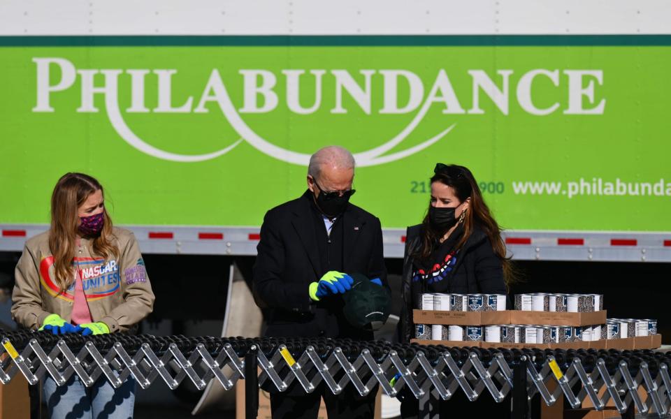 Joe Biden(C),stands with his grandaughter Finnegan(L) and daughter Ashley(R) as they pack up food donations at Philabundance, Philadelphia's largest hunger relief organisation  - AFP