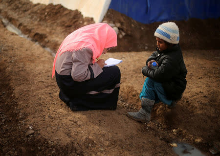 A displaced Iraqi girl writes outside a tent school set by United Nations Children's Fund (UNICEF) at Hassan Sham camp, east of Mosul, Iraq December 8, 2016. REUTERS/Mohammed Salem