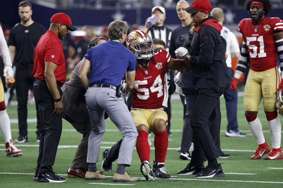 San Francisco 49ers middle linebacker Fred Warner (54) is assisted by team staff after suffering an unknown injury in the second half of an NFL wild-card playoff football game against the Dallas Cowboys in Arlington, Texas, Sunday, Jan. 16, 2022. (AP Photo/Ron Jenkins)