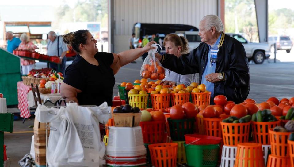 Erica Garcia helps customers Joe Williams and Brenda Northcutt at her stall at the South Carolina State Farmer’s Market on Friday, March. 24, 2023.