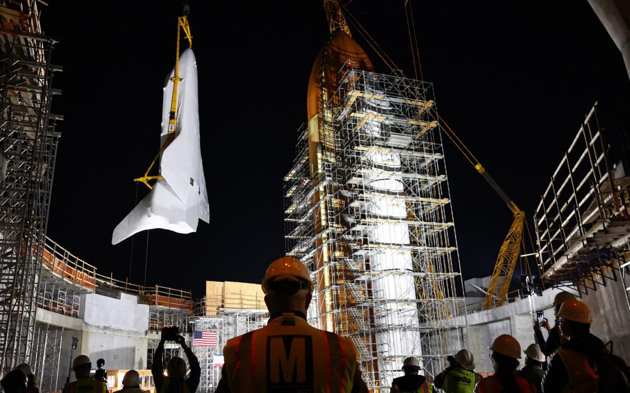 The retired NASA Space Shuttle, Endeavour, covered in protective white wrapping, is lifted into place