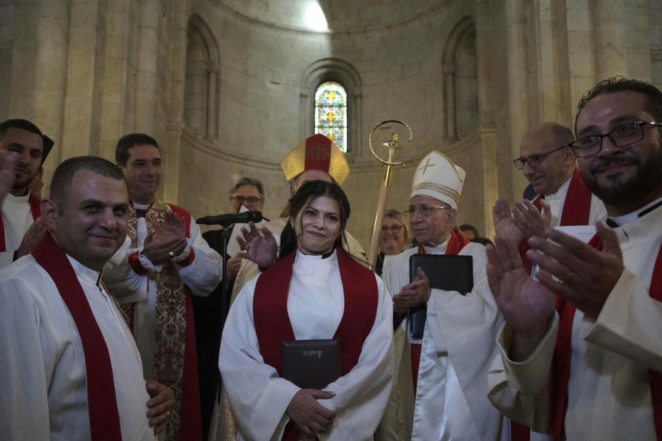 Sally Ibrahim Azar, center, a Palestinian Christian and Council member of the Lutheran World Federation is applauded by clergy after she was ordained as the first female pastor in the Holy Land, in the Old City of Jerusalem, Sunday, Jan. 22, 2023. (AP Photo/Maya Alleruzzo)
