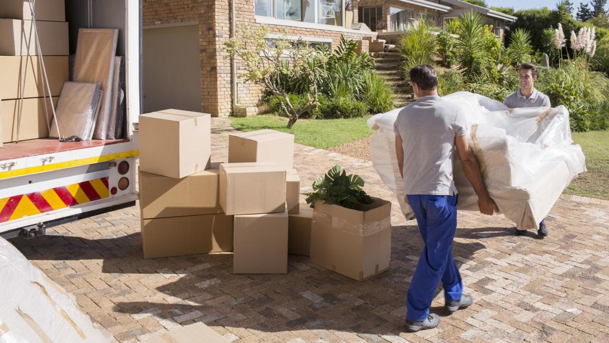 movers carrying sofa from moving van to house