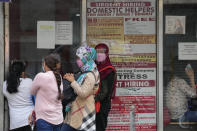 Women stand beside a sign about hiring domestic helpers for the middle east outside an office in Manila, Philippines on Monday, Oct. 18, 2021. Apple once threatened to pull Facebook and Instagram from its app store over concerns about the services being used to trade and sell maids in the Mideast, according to documents obtained by The Associated Press. (AP Photo/Aaron Favila)