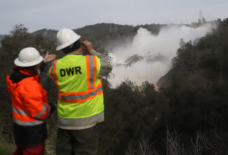 Staff with the California Department of Water Resources watch as water is released from the Lake Oroville Dam after an evacuation was ordered for communities downstream from the dam in Oroville, California. REUTERS/Jim Urquhart