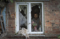 FILE - A local resident places a vase with flowers on a broken window in his house damaged by the Russian shelling in Bakhmut, Donetsk region, Ukraine, Sunday , June 26, 2022.(AP Photo/Efrem Lukatsky, File)