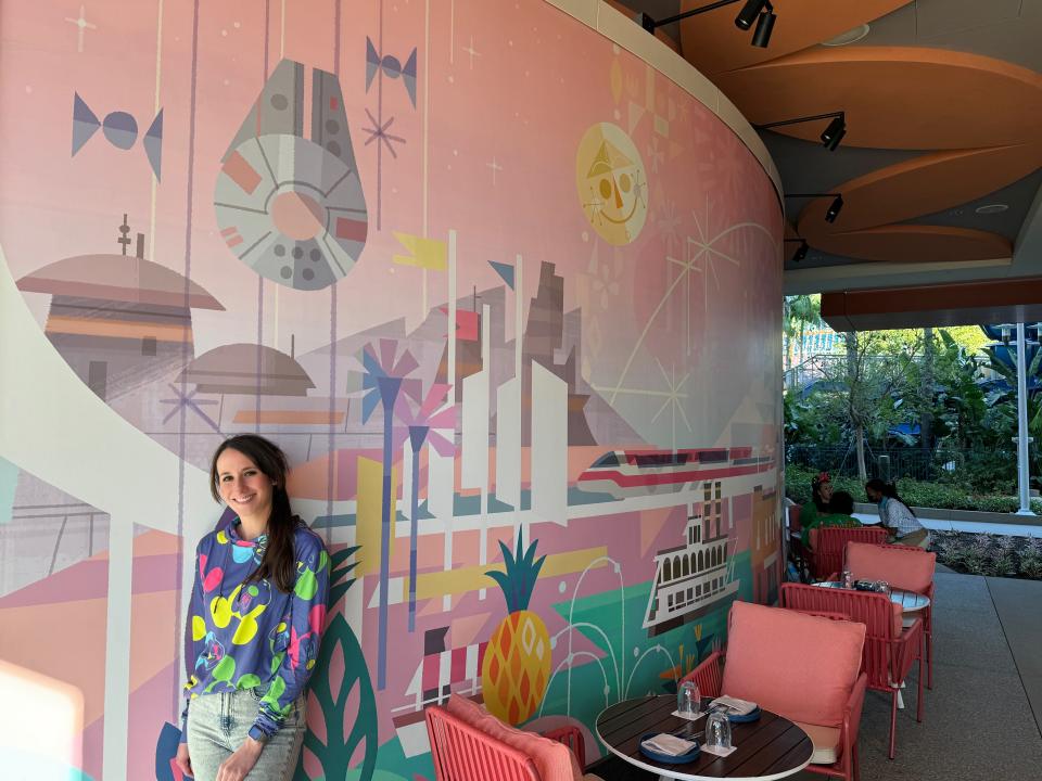 Author Brooke McDonald posing with colorful mural in Palm Breeze Bar