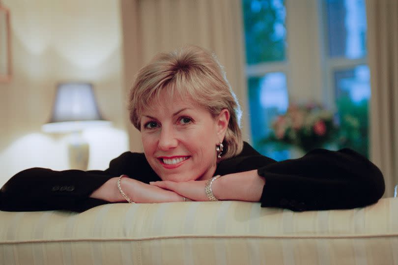 Jill Dando leaning over the back of a sofa smiling