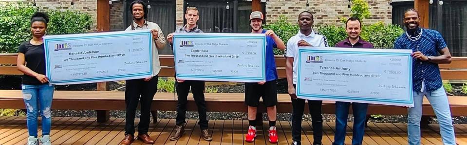 DOORS graduates and others pose with the checks they have received for their work.