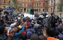 Oscar Pistorius, back to camera center rear, before he climbs into a car to leave the high court after the third day of his trial in Pretoria, South Africa, Wednesday, March 5, 2014. Pistorius is charged with murder in the shooting death of girlfriend Reeva Steenkamp in the pre-dawn hours of Valentine's Day 2013. (AP Photo/Schalk van Zuydam)