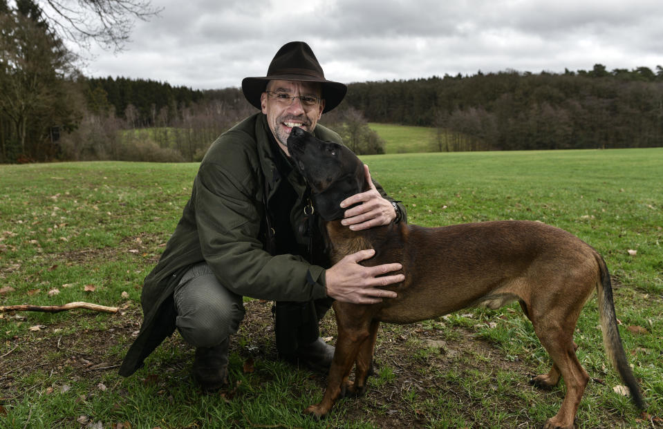 In this Dec. 7, 2018 photo Dirk Gratzel poses for a photo with his dog at his hunting ground in Stollberg, Germany. Gratzel counts his carbon emissions . The software entrepreneur from Germany is among a growing number of people looking for ways to cut their personal greenhouse gas emissions from levels that scientists say are unsustainable if global warming is to be curbed. (AP Photo/Martin Meissner)