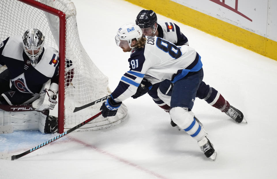 Winnipeg Jets left wing Kyle Connor, front right, drives past Colorado Avalanche right wing Logan O'Connor, back right, to shoot against Avalanche goaltender Alexandar Georgiev in the third period of an NHL hockey game Thursday, April 13, 2023, in Denver. (AP Photo/David Zalubowski)
