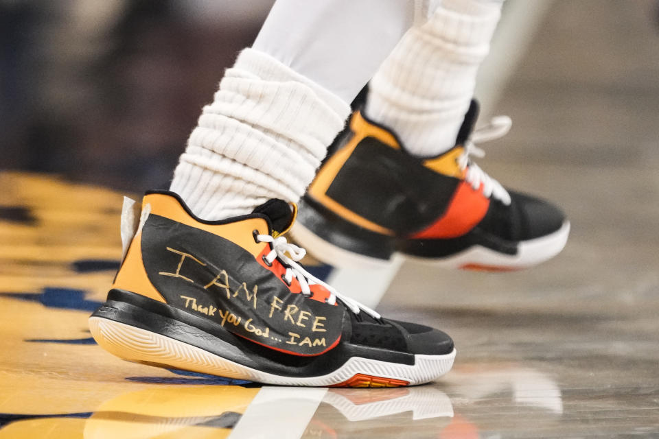 Brooklyn Nets guard Kyrie Irving (11) wears sneakers with logos covered in tape with the words "I AM FREE Thank you God … I AM" written in gold colored marker during the second half of an NBA basketball game against the Charlotte Hornets, Wednesday, Dec. 7, 2022, in New York. (AP Photo/John Minchillo)