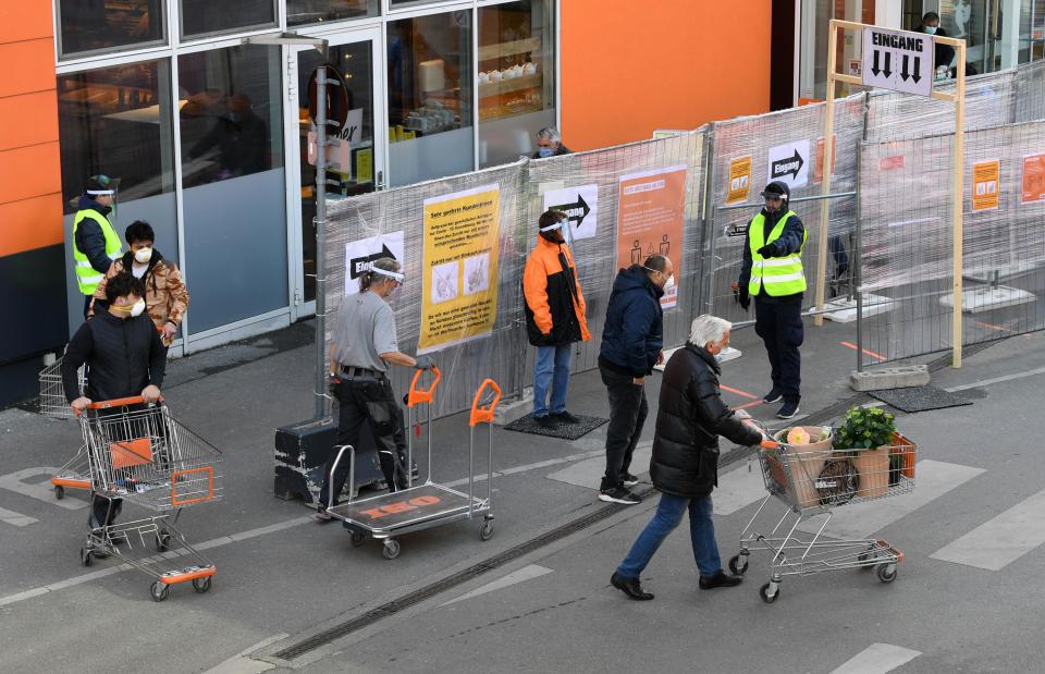 Customers wearing face masks push shopping carts in front of a DIY store in Vienna, Austria, after it re-opened on April 14, 2020, following a "shutdown" in a measure to limit the spread of the new coronavirus. (Photo by HELMUT FOHRINGER / APA / AFP) / Austria OUT (Photo by HELMUT FOHRINGER/APA/AFP via Getty Images)