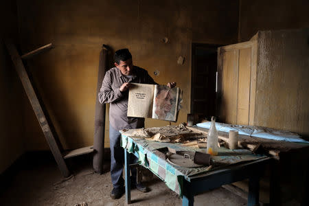 A man holds a book inside a deserted church in an area recently cleared of mines and unexploded ordnance in a project to clear the area near Qasr Al-Yahud, a traditional baptism site along the Jordan River, near Jericho in the occupied West Bank, December 9, 2018. REUTERS/Ammar Awad