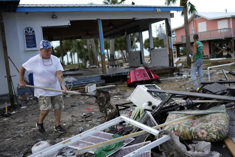 Employee Lisa Bell dumps out a shovel full of mud as business owners and employees start cleaning up at the storm-damaged business The Marina, in Horseshoe Beach, Fla., Thursday, Aug. 31, 2023, one day after the passage of Hurricane Idalia. (AP Photo/Rebecca Blackwell)