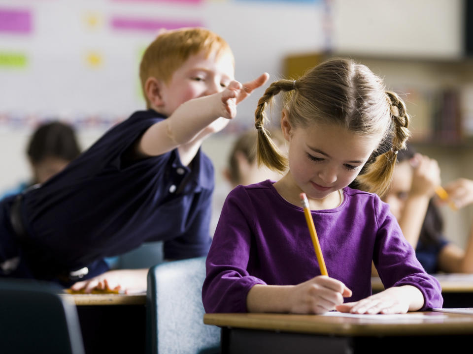 a young boy reaching for a girl's pigtails