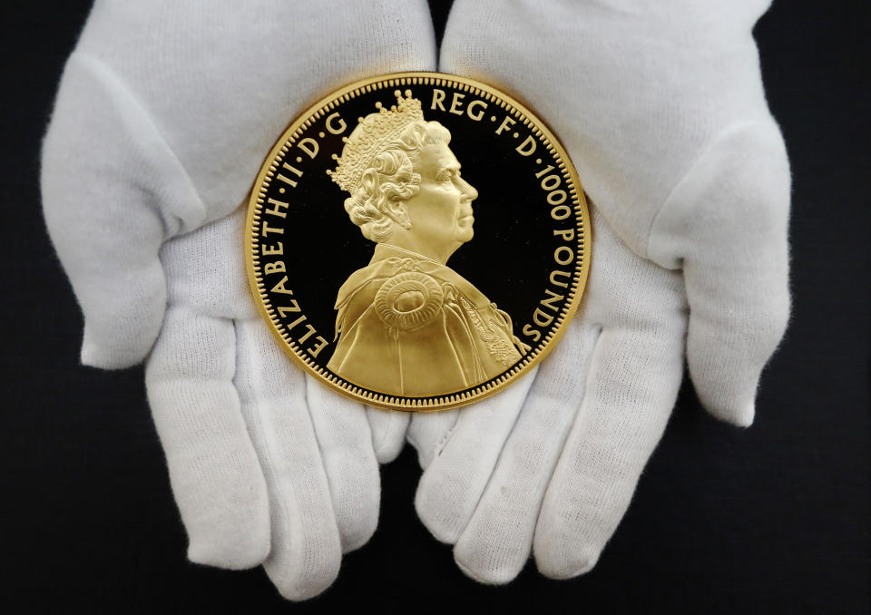 King Charles Curator John Keyworth poses with a newly minted Diamond Jubilee gold coin at the Bank of England Museum in London June 22, 2012. The coin, one of 60 struck to celebrate the Diamond Jubilee of Britain's Queen Elizabeth,  weighs one kilo and is valued at 60,000 GBP. The exhibition 