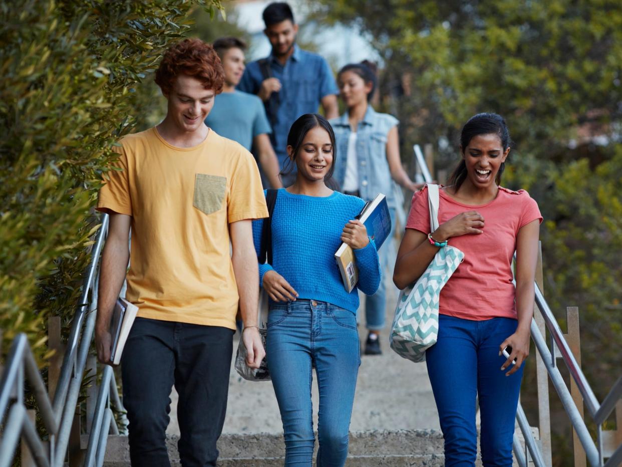 Three students walk down stairs laughing