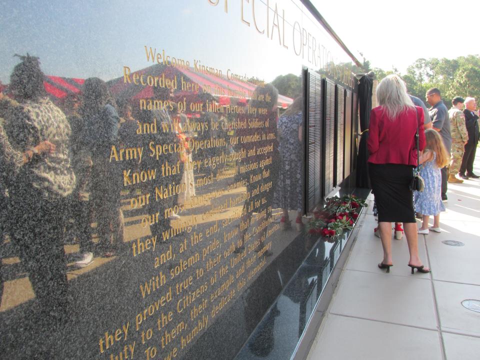 Family members scan the U.S. Army Special Operations Command's memorial wall for their loved ones names after a ceremony Thursday, May 23, 2024, at Fort Liberty.