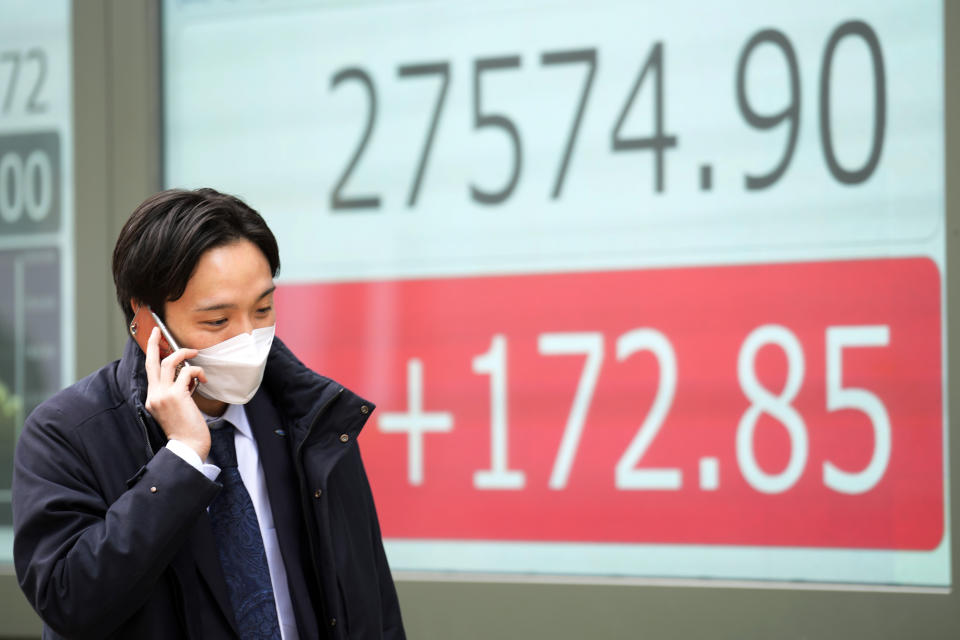 A person wearing a protective mask walks in front of an electronic stock board showing Japan's Nikkei 225 index at a securities firm Friday, Feb. 3, 2023, in Tokyo. Asian shares were trading mixed Friday ahead of a closely watched U.S. jobs report that may affect global interest rates. (AP Photo/Eugene Hoshiko)