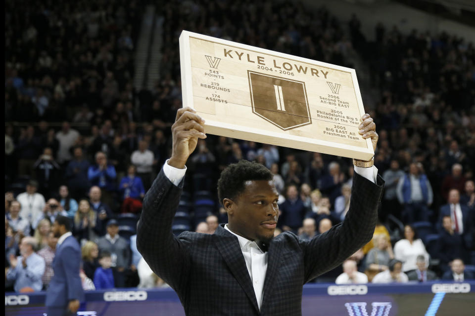 Kyle Lowry, a former Villanova player and current Toronto Raptors player, holds up a plaque during a ceremony honoring him during halftime of an NCAA college basketball game between Villanova and St. John's, Wednesday, Feb. 26, 2020, in Villanova, Pa. (AP Photo/Matt Slocum)