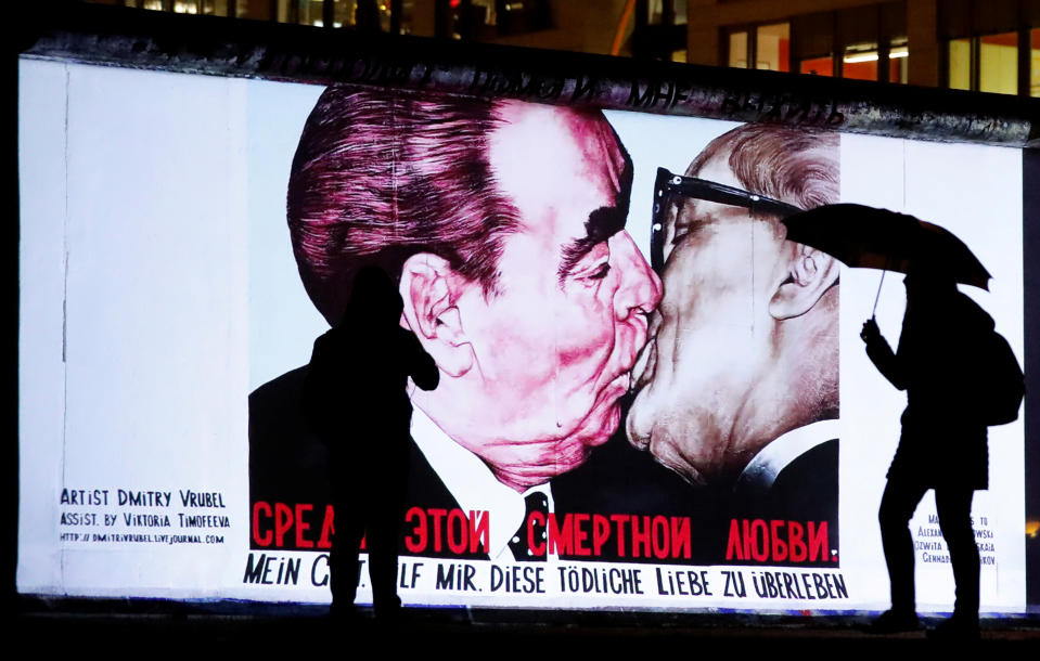 People stand in front of a projection depicting former Soviet leader Leonid Brezhnev kissing his East German counterpart Erich Honecker, on the East Side Gallery, the largest remaining part of the former Berlin Wall, in Berlin, Germany, November 4, 2019. On November 9th Germany will mark the 30th anniversary of the fall of the Berlin Wall (Berliner Mauer) in 1989. REUTERS/Fabrizio Bensch     TPX IMAGES OF THE DAY