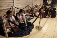 Sing Nguyen (L), 27, and his wife Ngan who is wearing a mask for the haze, 27, from Vietnam, queue overnight to be the first in line for the launch of the new Apple iPhone 6s mobile phone at a mall in Singapore September 25, 2015. The Nguyens who are the first in the queue started queuing since Wednesday 10pm. The 3-hour Pollutant Standards Index (PSI) reached a high of 341 at 5am on Friday. REUTERS/Edgar Su