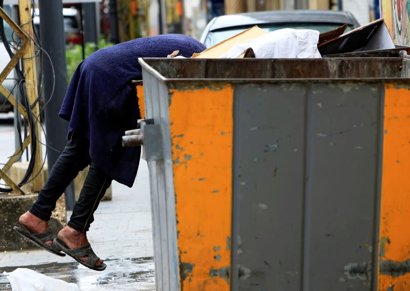 A man searches through a garbage bin