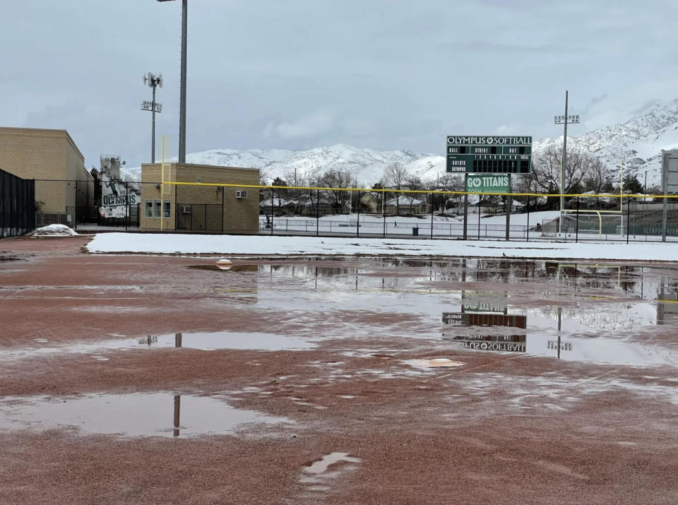 The Olympus High softball scoreboard can be seen reflecting in a pool of water on March 31, 2023. Soggy conditions have forced the postponement or cancellation of numerous high school games this spring. | Deseret News