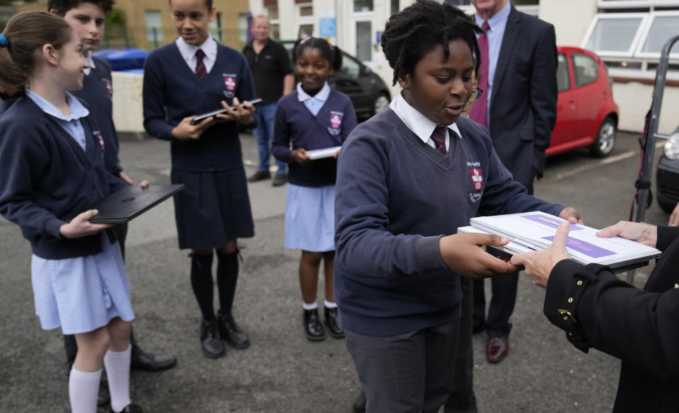 Samson Solola, receives a couple of reconditioned laptops for pupils at the Holy Family Catholic Primary School in Greenwich in London, Monday, May 24, 2021. (AP Photo/Alastair Grant)