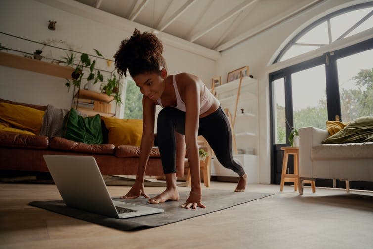 Young woman exercises to a video on her laptop.