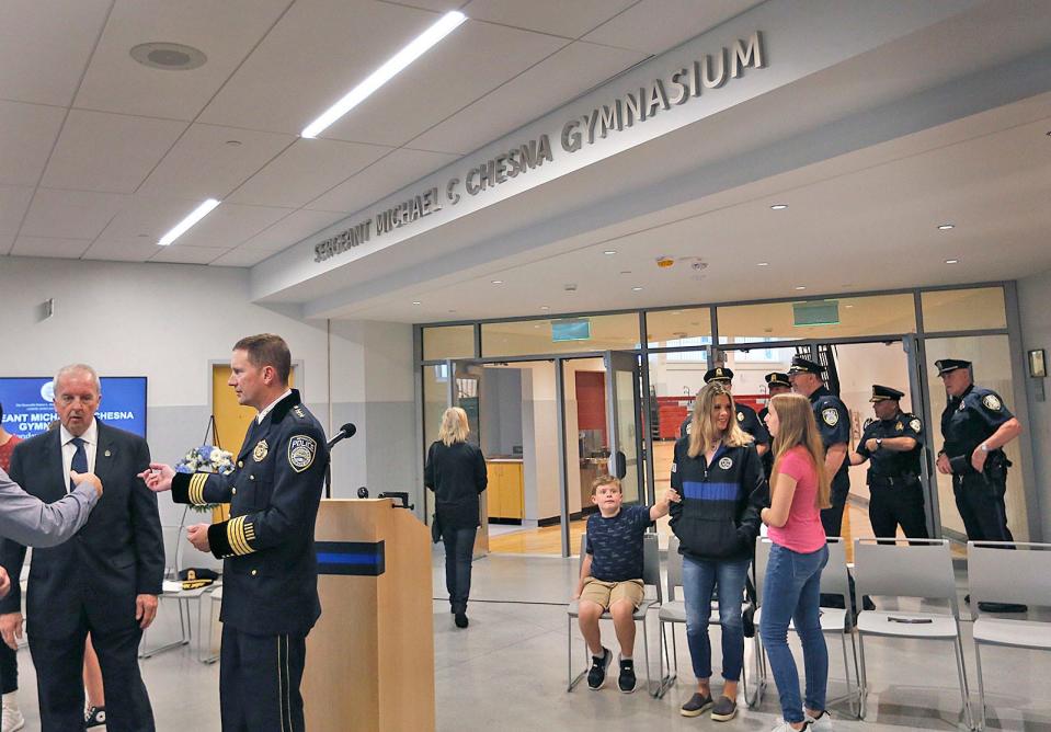 People gather near the entrance of the Sgt. Michael Chesna Gymnasium at Chapman Middle School in Weymouth to dedicate the gym to Chesna on Monday, Sept. 18, 2023.