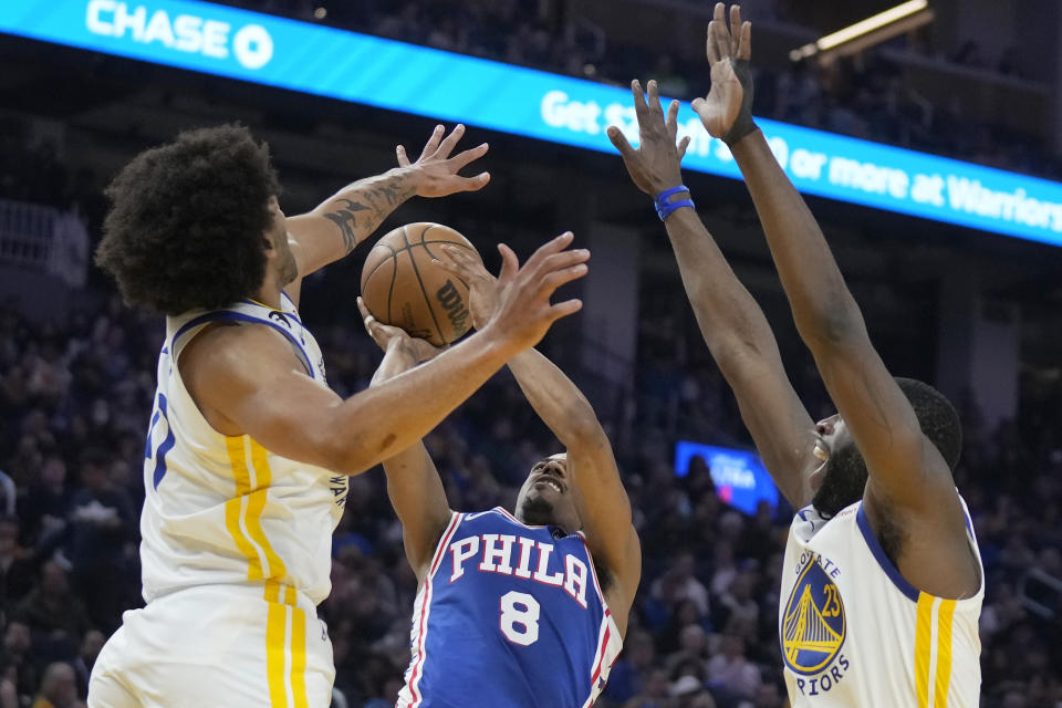 Philadelphia 76ers guard De'Anthony Melton (8) shoots between Golden State Warriors forwards Anthony Lamb, left, and Draymond Green during the first half of an NBA basketball game in San Francisco, Friday, March 24, 2023. (AP Photo/Jeff Chiu)